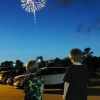 Two boys watch the Fulton Tourism fireworks show from a store parking lot July 4.