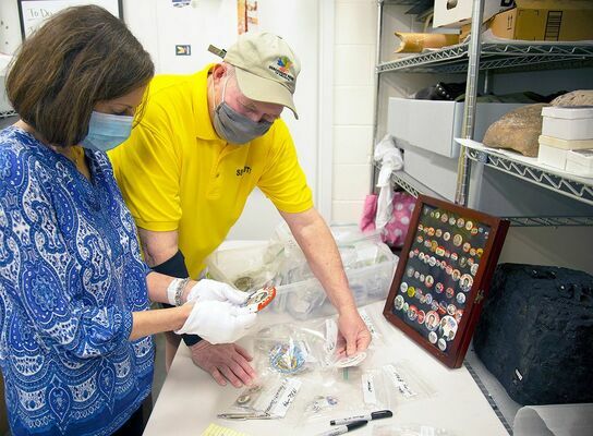 Discovery Park docent Lisa Sears and security guard Randy Anding look over the campaign buttons that will be on display beginning Oct. 8. Anding began collecting campaign buttons in the mid-1970s after a visit to Jimmy Carter’s campaign headquarters. (Photo submitted)