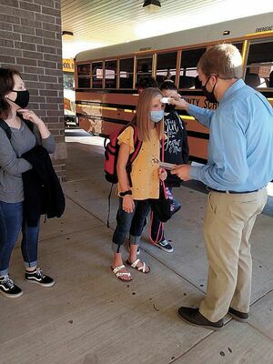 TEMP CHECK – As featured on page one of the Aug. 19 edition of The Current, South Fulton Middle School teacher David Whitesell assisted in checking temperatures of SFMS/SFHS students as they exited the bus to begin classes Aug. 17, with masks required.